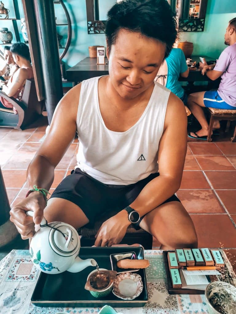 Andy pouring a cup of tea from a teapot, Reaching Out Tea House, best things to do in Hoi An, Vietnam