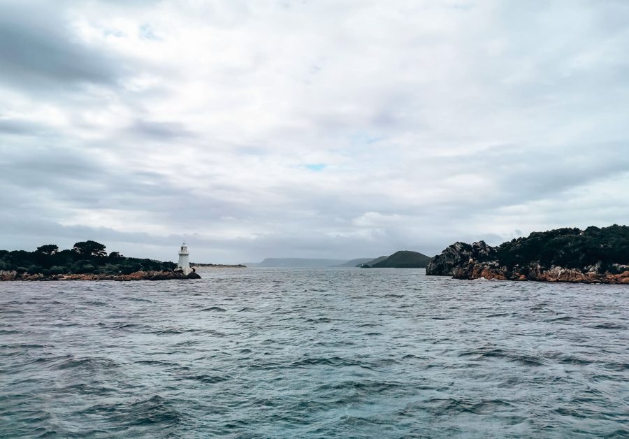 The rough open ocean looking towards a lighthouse at Hells Gates, Strahan, places to visit in Tasmania