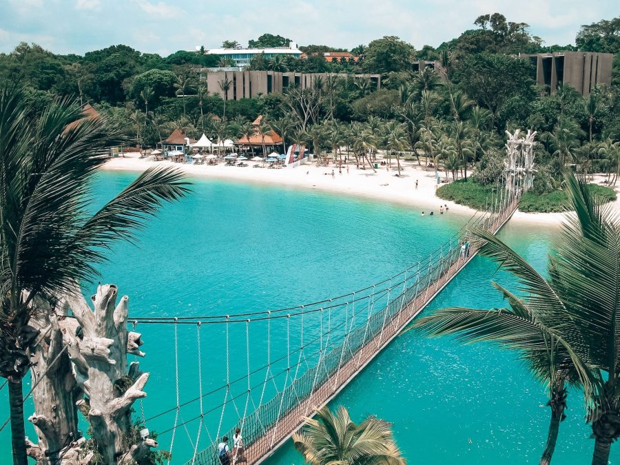 A rope bridge hanging above the ocean immersed in tropical greenery and a white sand beach on Sentosa Island is the place to relax in Singapore