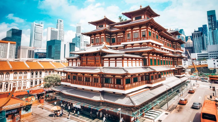 Grand exterior of the Buddha Tooth Relic Temple with towering skyscrapers behind in Chinatown, where to stay in Singapore