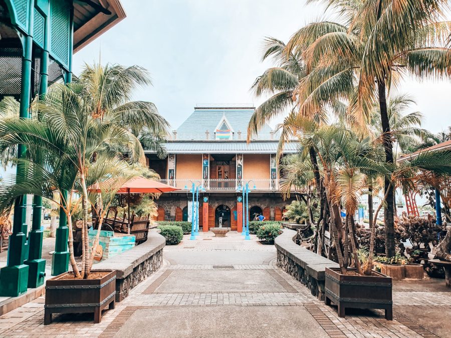 The colourful exterior of the Blue Penny Museum with palm trees at the front in Port Louis, Mauritius