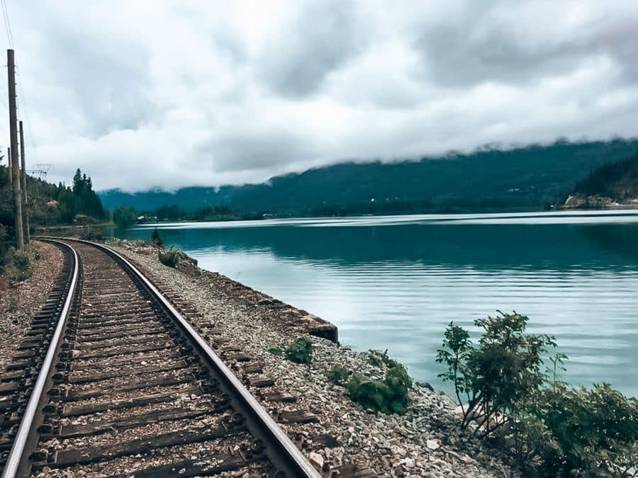 Railway track next to the tranquil Green Lake shrouded in mist, Whistler, British Columbia, Canada