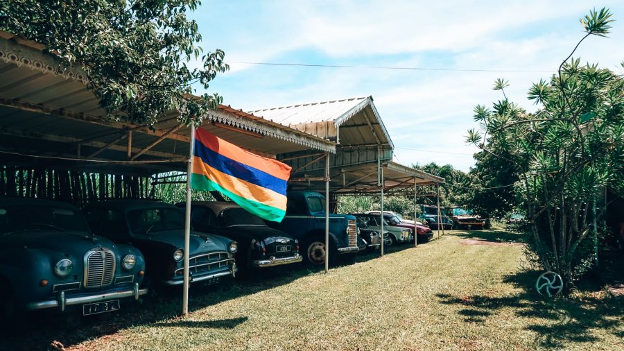 A row of vintage cars at Chez Tante Athalie with the Mauritian flag, Mauritius