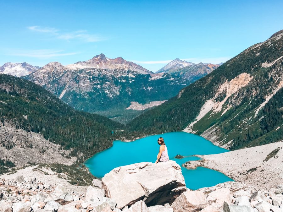 Helen sat on a ledge by Matier Glacier overlooking Joffre Lakes in Whistler in summer, Canada, British Columbia