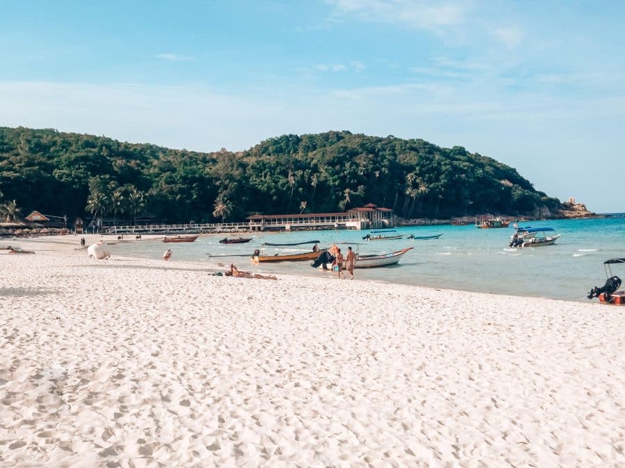 A gorgeous white sand beach lined with trees and turquoise ocean, Perhential Islands, one of the best places to visit in Malaysia