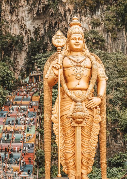 A huge gold statue standing next to colourful stairs, Kuala Lumpur, places to visit in Malaysia