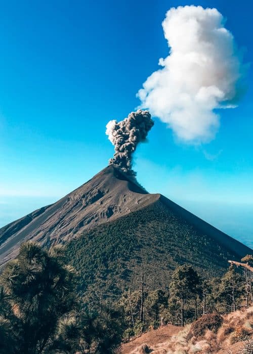 The view hiking down Volcan Acatenango over to Volcan Fuego erupting in the distance; one of the best things to do in Guatemala