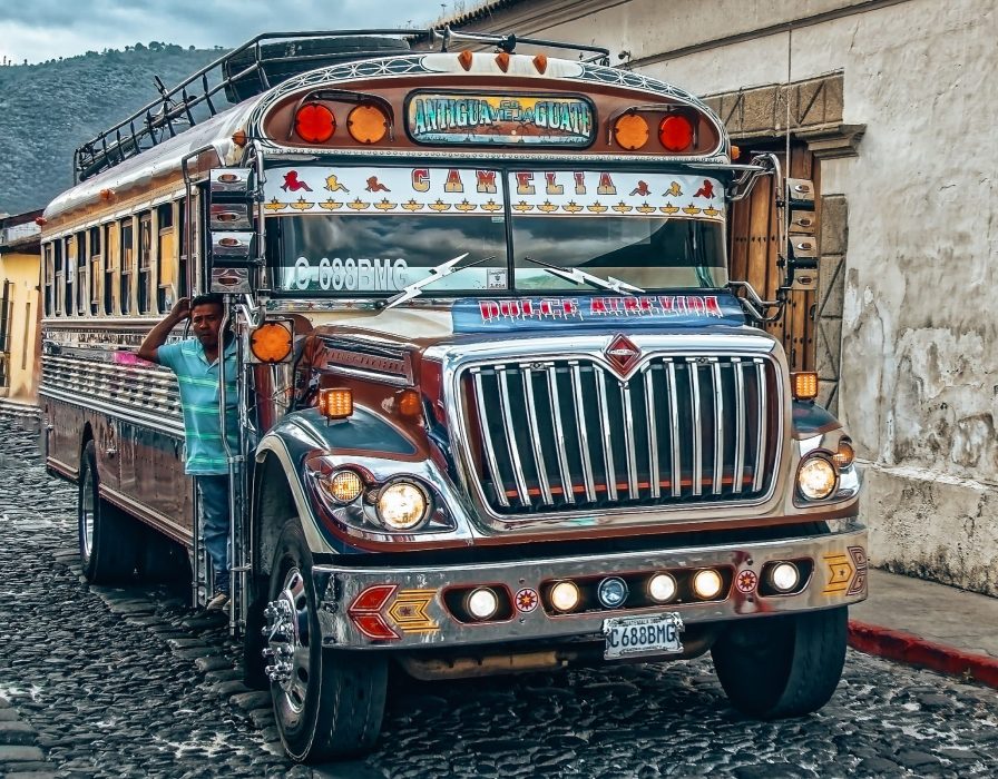 A colourful chicken bus with a local poking their head out the door, Guatemala, Central America