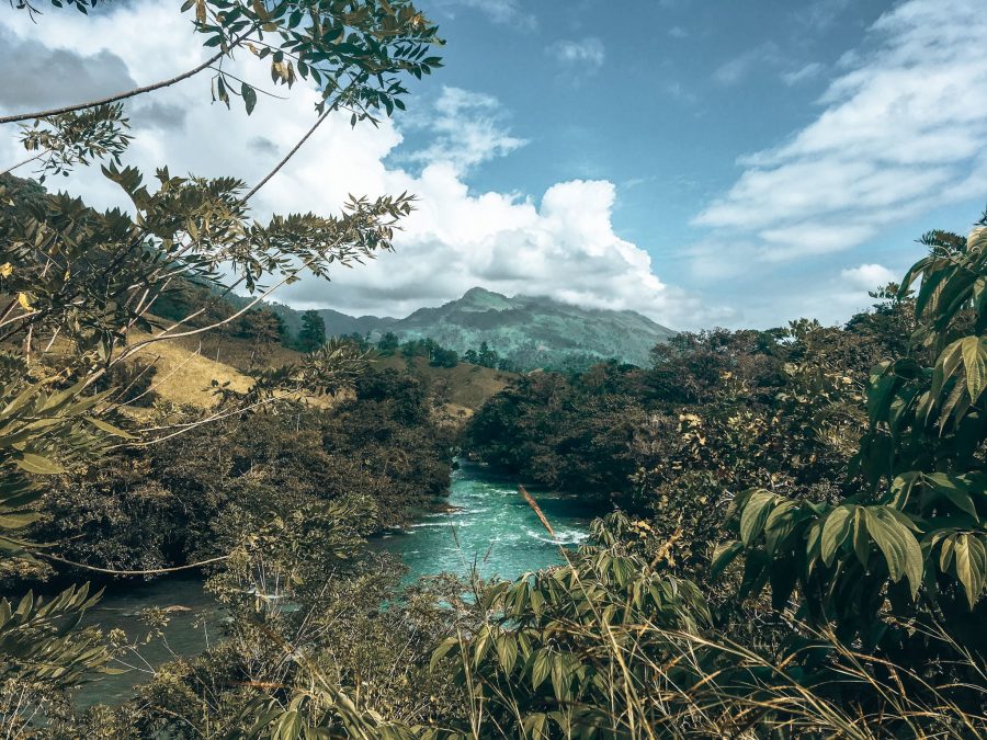 Thick jungle and towering mountains with a river flowing through in Lanquin, Guatemala