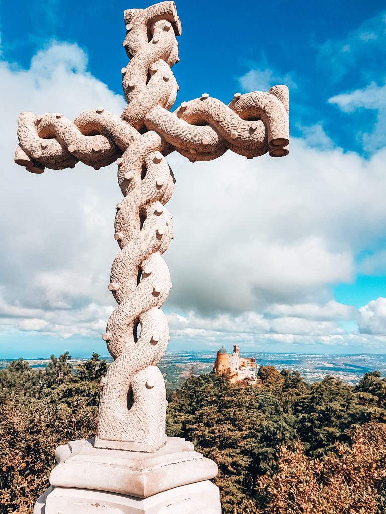 Pena Palace protruding through the forest from the grand white cross of Cruz Alta, Sintra day trip from Lisbon, Portugal