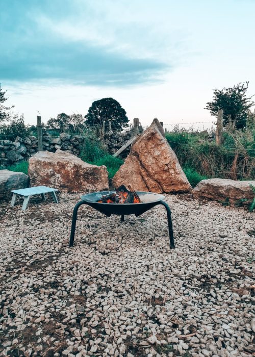 A firepit in Ruehill Campsite with a blue sky turning to evening in the Peak District, Derbyshire