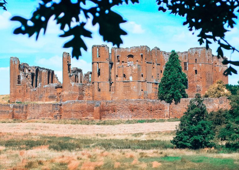 A magnificent view of Kenilworth Castle through the trees and surrounded by green countryside, Warwickshire