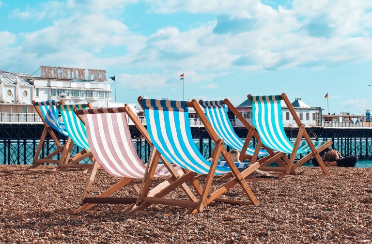 Colourful sunbeds on Brighton Beach in front of Brighton Pier, day trips from London, England