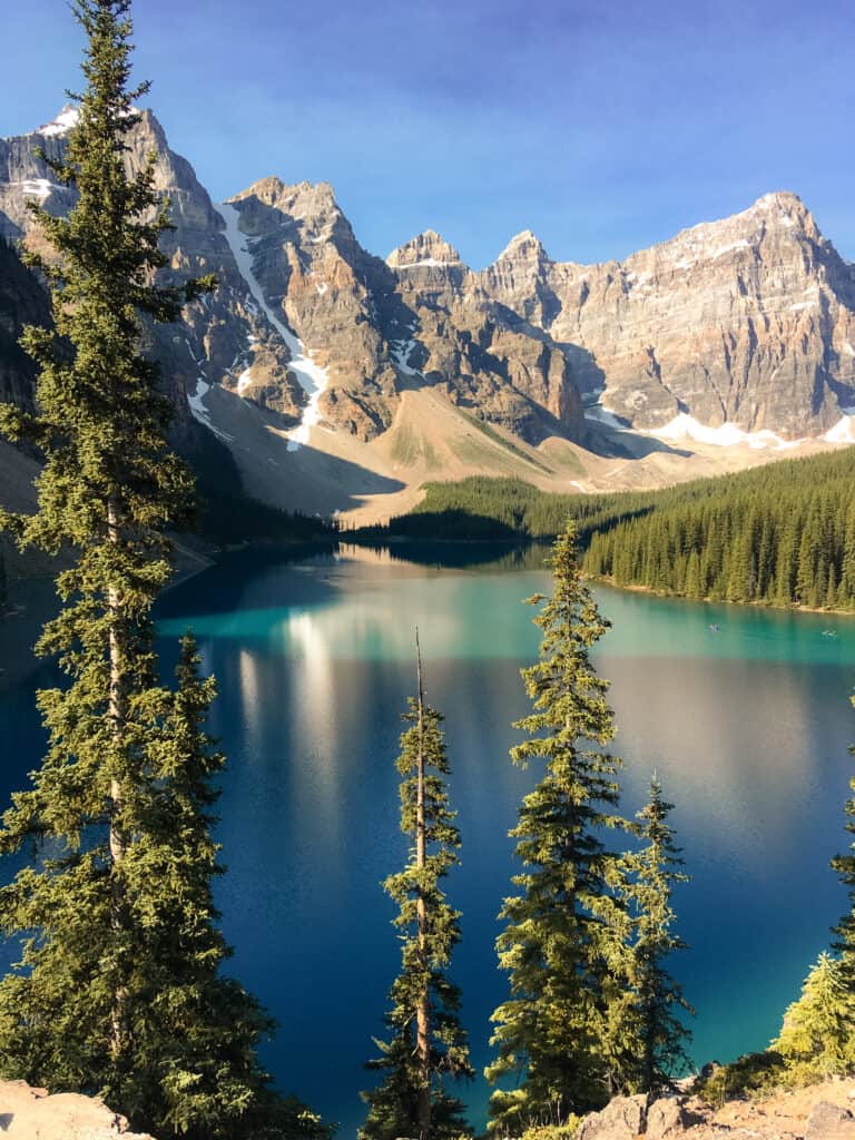 Moraine Lake shimmering in the sun nestled amongst towering mountain peaks, my favourite lake on my Calgary to Vancouver road trip