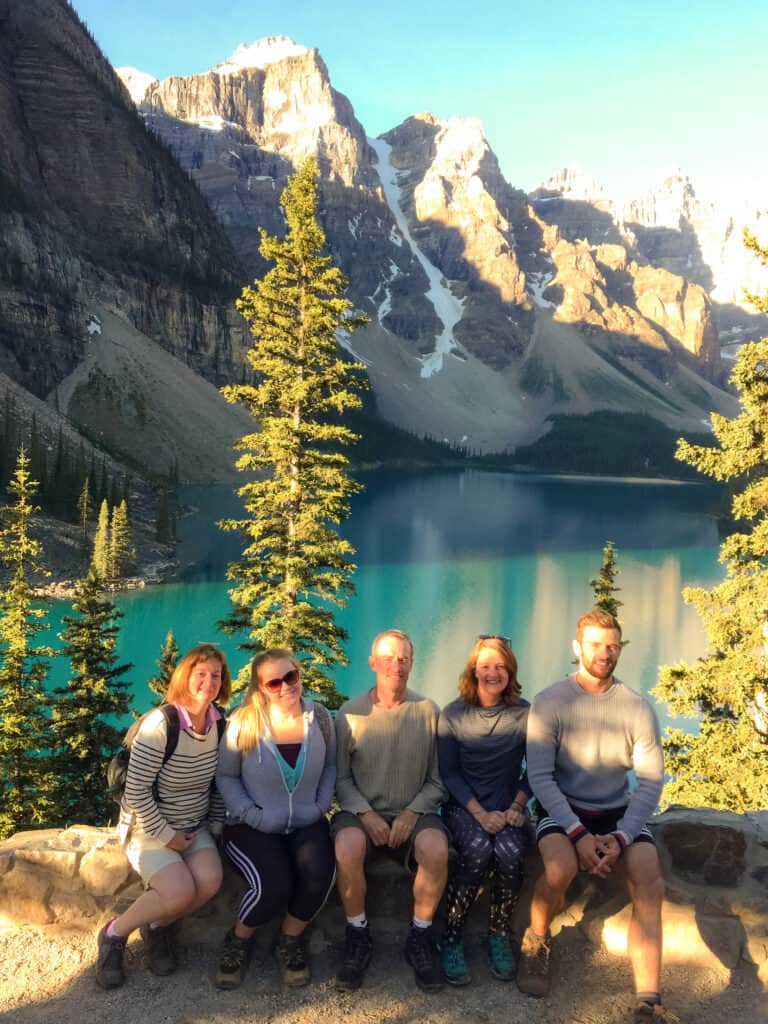 Helen with her family sat by the piercing blue Moraine Lake nestled below towering mountain peaks, Banff