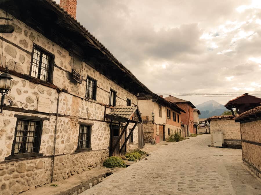 Old buildings lining the narrow cobbled streets with a mountain backdrop in Bansko's Old Town, Bulgaria