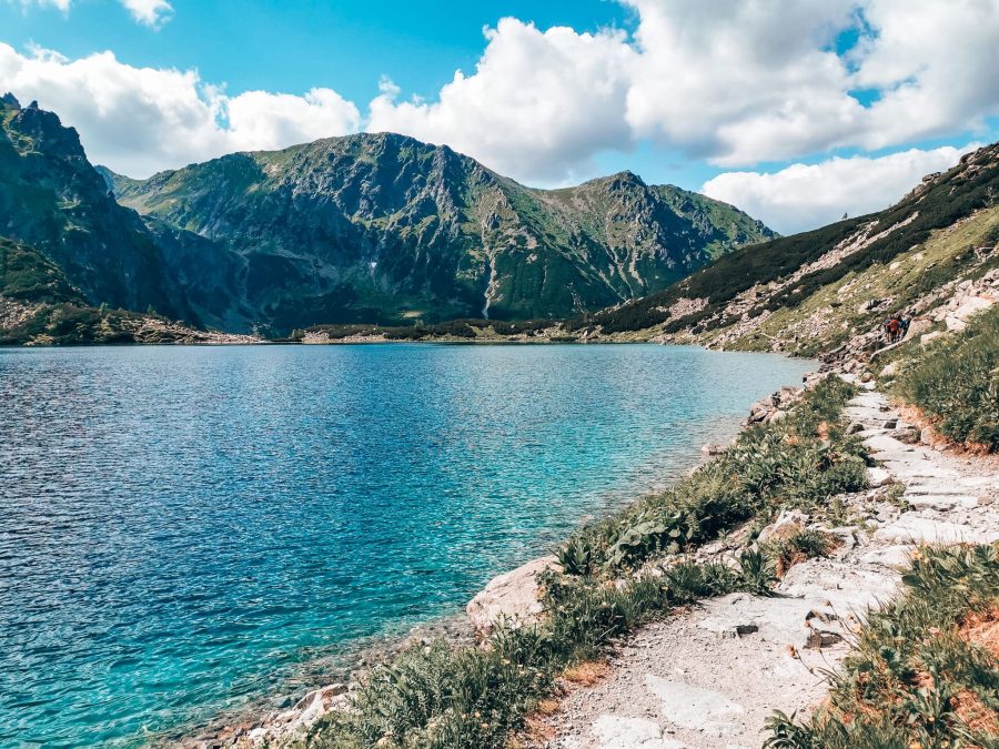 A narrow stone path alongside Morskie Oko with Tatra Mountains in the background, hiking Rysy Mountain, Poland