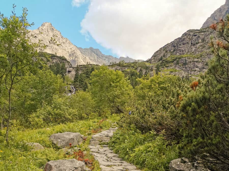Steep path surrounded by mountain peaks and greenery between Morskie Oko and Czarny Staw up Rysy Mountain, Zakopane, Poland