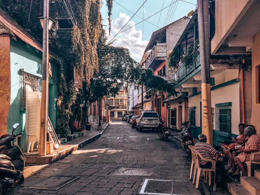 Colourful, quaint narrow streets with people sat outside on tables in Flores on your Guatemala itinerary, Central America