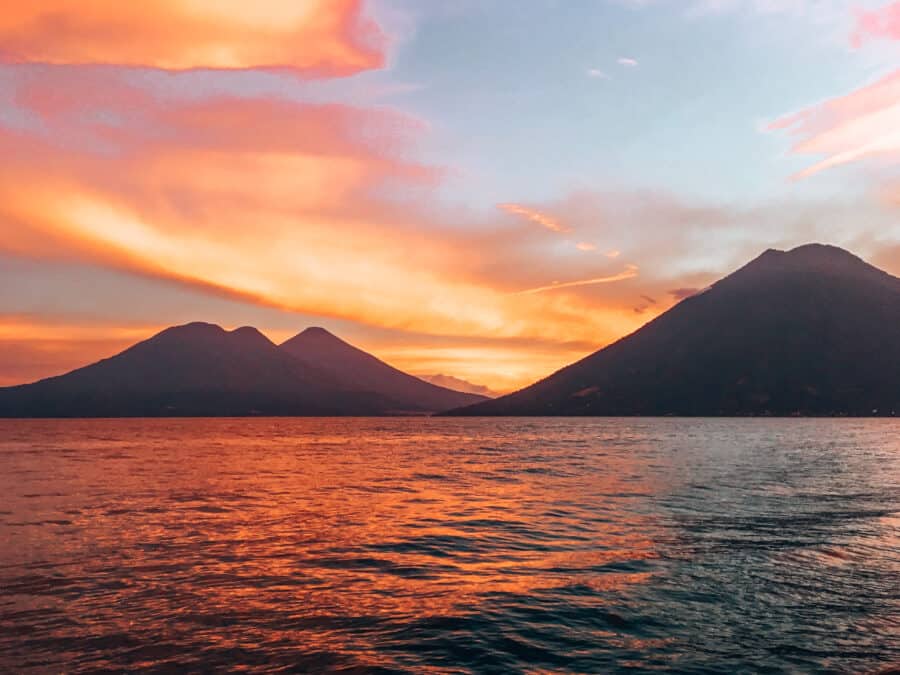 The silhouettes of two volcanoes with the sky lit up different reds and oranges at sunset, Guatemala