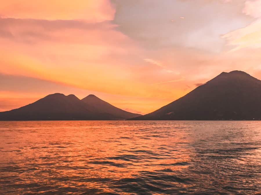 Different hues of reds and oranges lighting up Lake Atitlan and the volcanoes from San Marcos, Guatemala