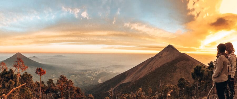 Stood overlooking Volcan Fuego and Volcano Agua at sunset with the sky lit up in fiery reds and oranes, Guatemala