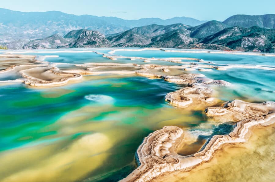 The turquoise pools of Hierve El Agua with a mountainous backdrop are one of the best things to do in Oaxaca, Mexico