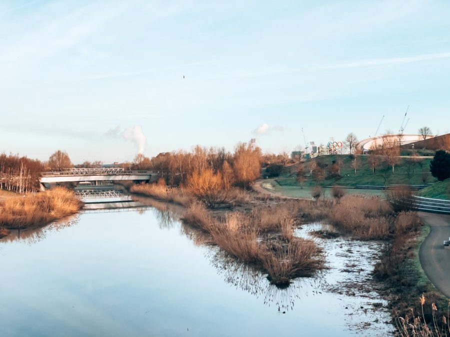 The tranquil River Lea running through Queen Elizabeth Olympic Park next to the Olympic rings, Stratford, East London, England