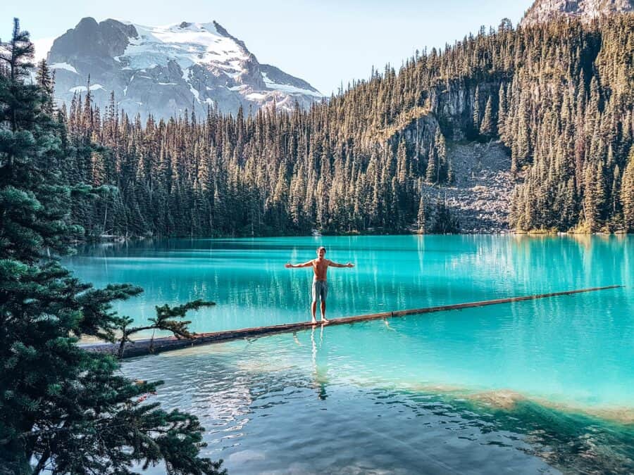 Andy stood on a log in Middle Joffre Lake with Matier Glacier looming above him, British Columbia, Canada