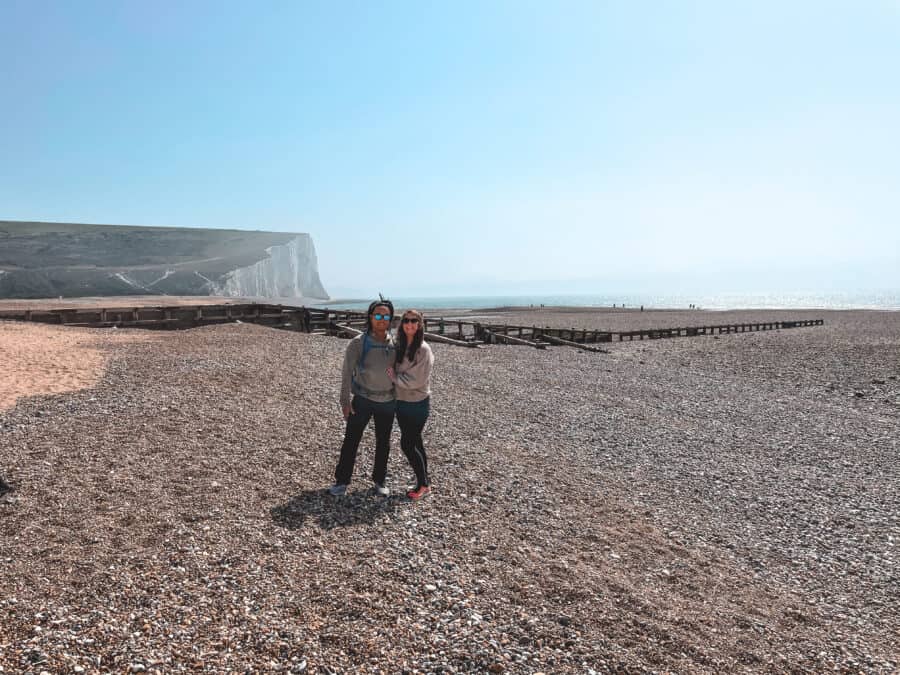 Helen and Andy standing on the shingle Cuckmere Haven Beach across to the Seven Sisters Cliffs, East Sussex, South Downs National Park