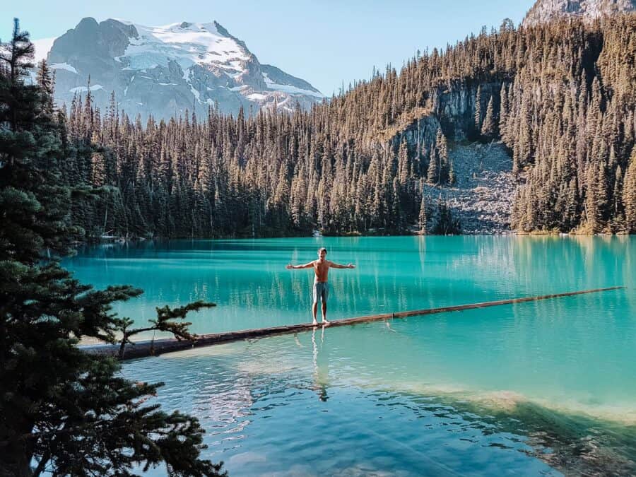 Andy stood on a log in Middle Joffre Lake with Matier Glacier towering above, Whistler, Canada