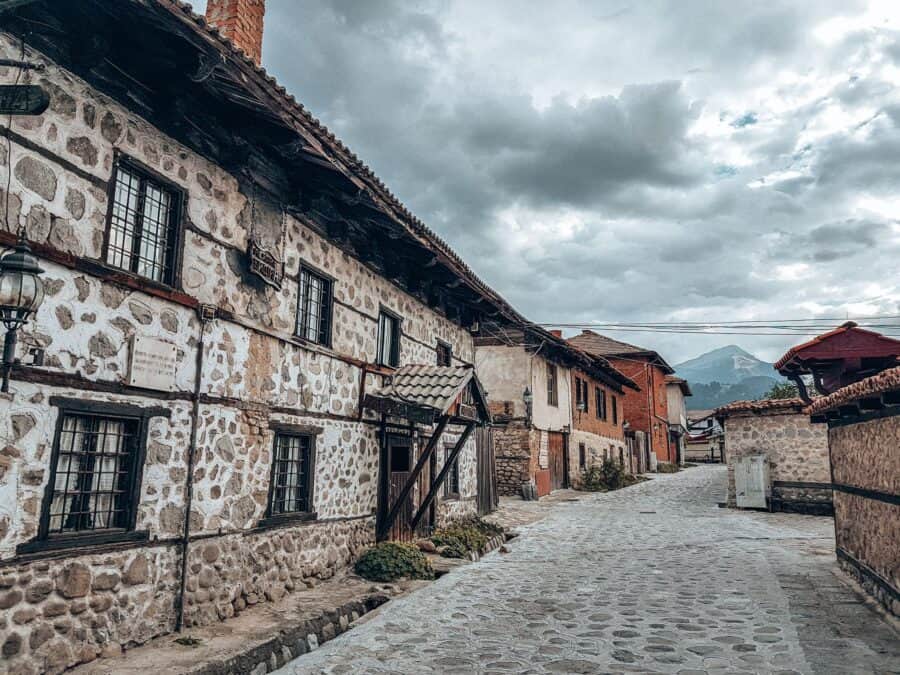 The quaint cobbled streets of Bansko Old Town with Mount Vihren looming in the distance, Bulgaria