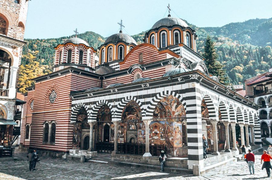 The elegant and impressive red, black and white stripped architecture of the Rila Monastery with a mountainous backdrop, things to do in Bulgaria