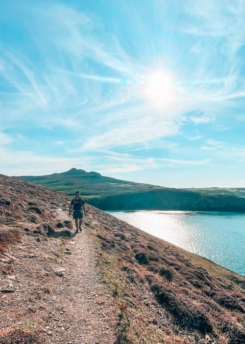 Andy walking along the Pembrokeshire Coast Path from Whitesands to Porthgain, next to the turquoise ocean, Wales