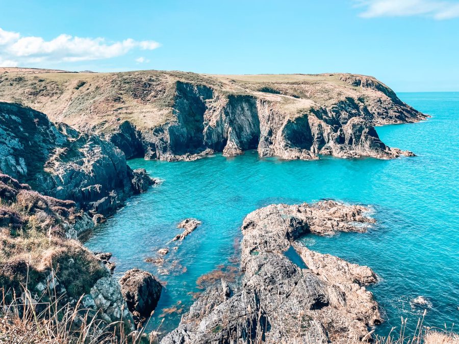 Rugged coastline towering above piercing blue ocean with jagged rocks in