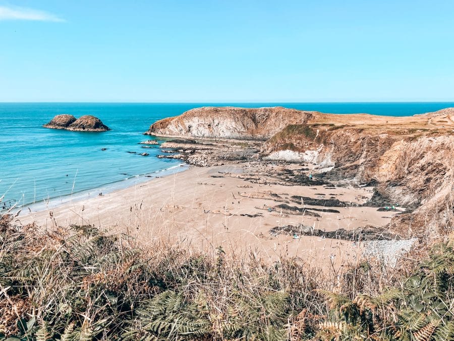 Volcanic rocks on and golden sand on Traeth Llyfn Beach, Pembrokeshire Coastal Path, Wales