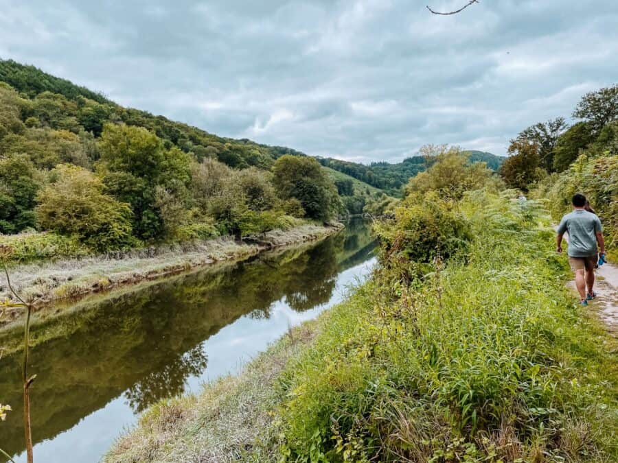 Andy walking next to the tranquil River Wye surrounded by greenery is one of the best things to do in the Wye Valley, Wales