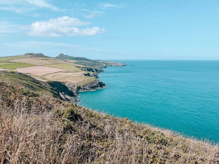 Countryside sloping down to the turquoise ocean along the Pembrokeshire Coast Path, Wales, UK