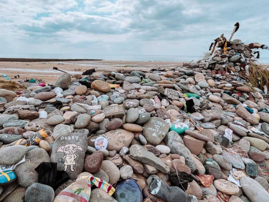 Piles of colourful stones and pieces of clothing on Dobby's Grave as a memorial at Freshwater West, Pembrokeshire, Wales, UK