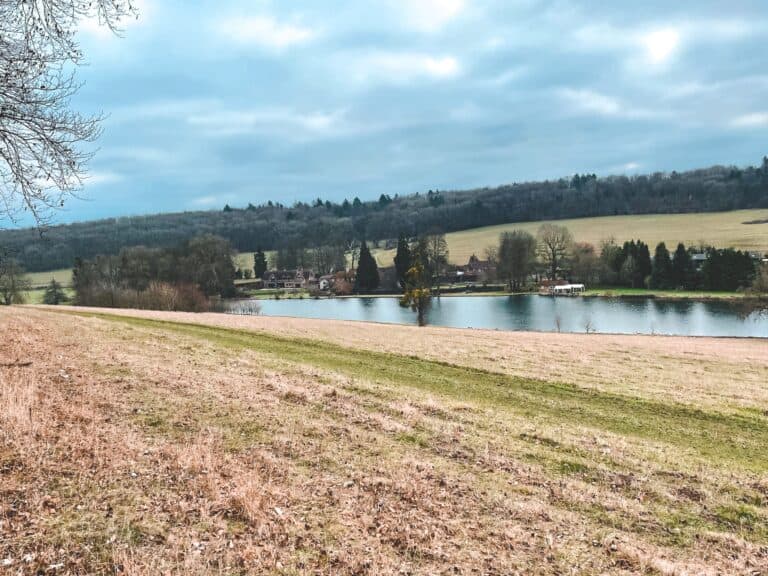 Views across the endless rolling green countryside over the River Chess to a lonely house on its banks on the Chess Valley Walk, UK