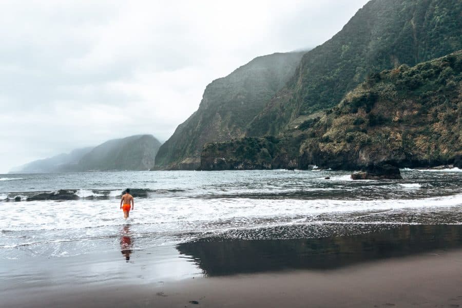 Andy walking into the sea with a dramatic mountain backdrop at Seixal Beach, places to visit in Madeira, Portugal