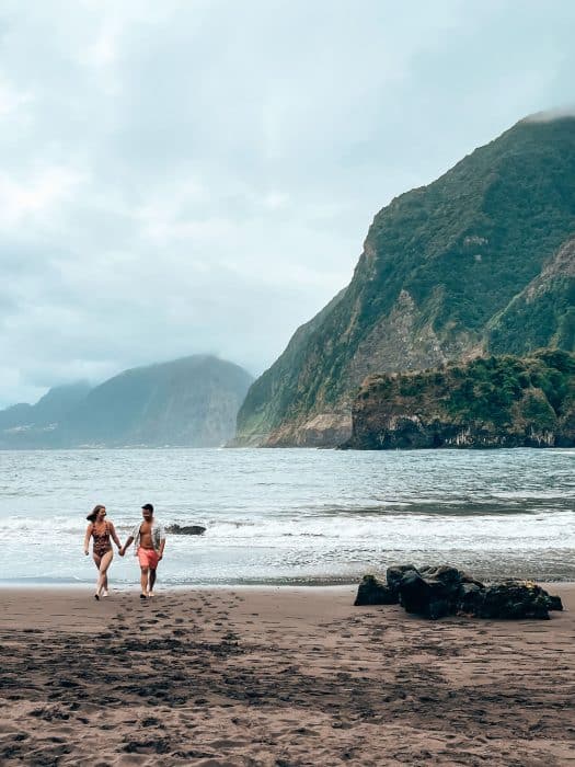 Andy and Helen walking out of the sea with an amazing mountain background at Seixal Beach, Madeira, Portugal