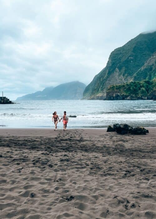 Andy and Helen walking out of the sea with an amazing mountain background at Seixal Beach, Madeira, Portugal