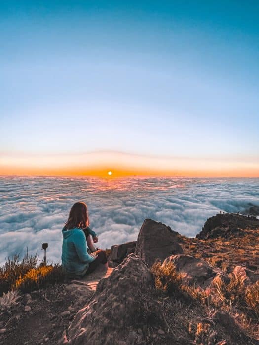 Helen sitting above the clouds at sunrise at Pico do Areeiro, Miradouro do Juncal, Madeira, Portugal