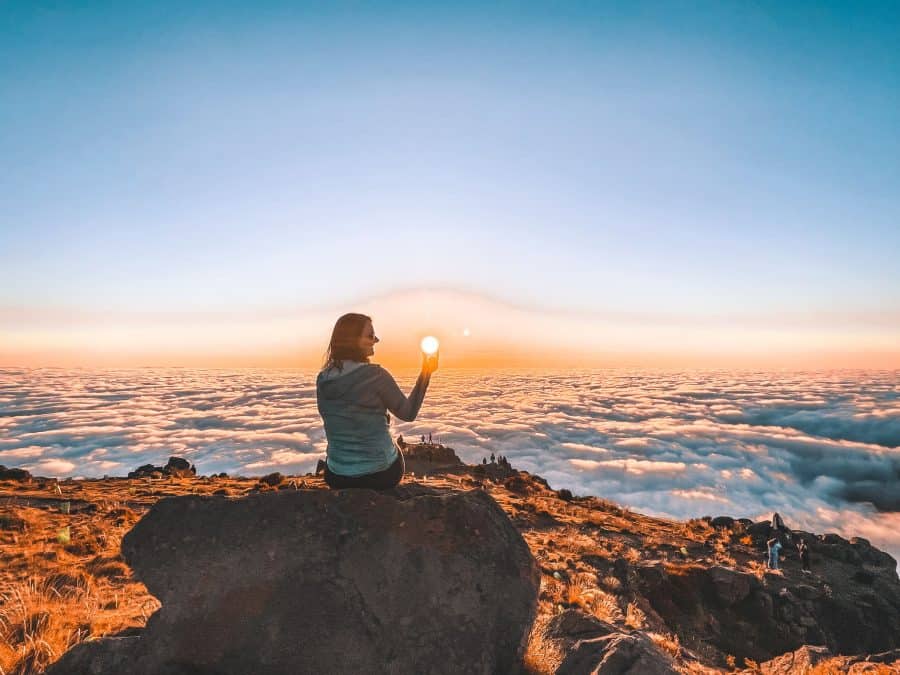 Helen sat at the Pico do Arieiro viewpoint at sunrise above the clouds, Madeira, Portugal