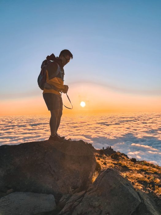 Andy standing on a rock above the clouds at sunrise at Pico do Areeiro, Miradouro do Juncal, Madeira, Portugal