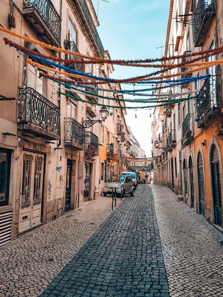 A quaint cobbled street lined with old yellow buildings in Bairro Alto, places to visit in Lisbon Portugal