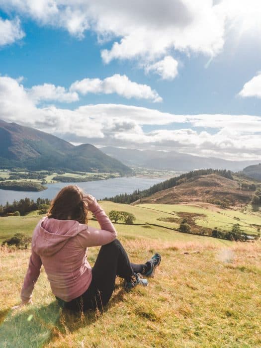 Helen sitting on the grass overlooking Bassenthwaite Lake at the base of Skiddaw, best things to do in the Lake District