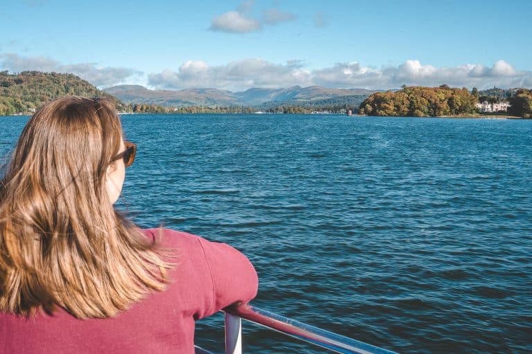 Helen sat on a boat looking out across Lake Windermere and the surrounding mountains is one of the top things to do in the Lake District, UK