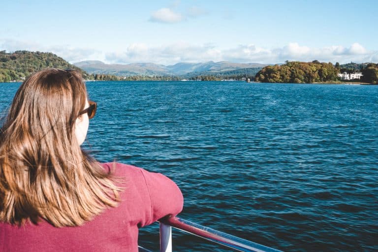 Helen sat on a boat looking out across Lake Windermere and the surrounding mountains is one of the top things to do in the Lake District